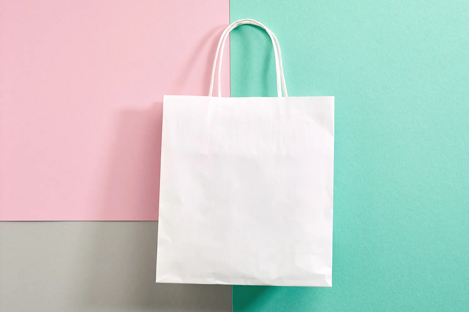Weiße Papier-Geschenktüte auf farbigem Hintergrund