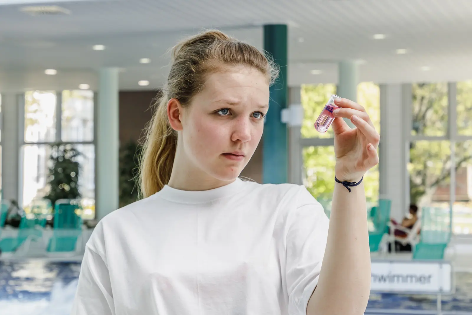 Eine junge Frau schaut eine Wasserprobe im Laborglas an.